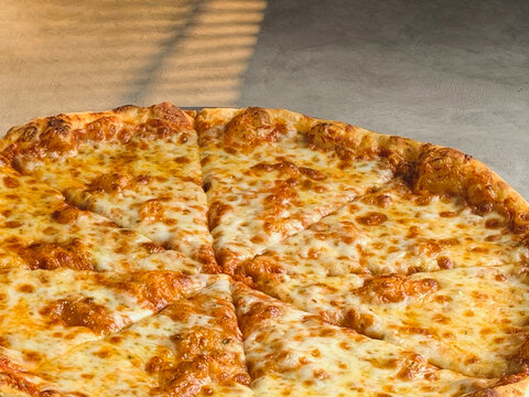 New York style pizza with melted cheese and base tomato sauce close-up.