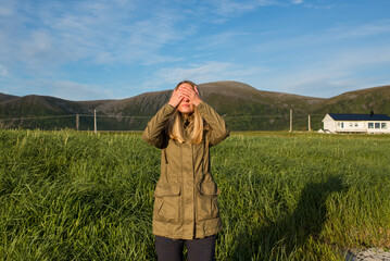 Young woman covering her eyes with her hands. Tourist attraction in Norway. Amazing scenic outdoor...