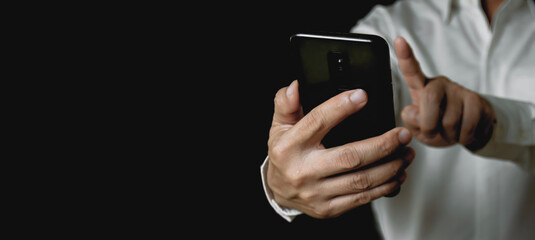Businessman hand holding and using a smartphone On black background, communication technology concept social network work online