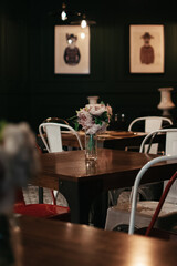 Jarrón con flores rosas encima de una mesa de madera oscura con el fondo oscuro 