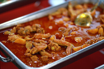Close up chicken curry serving on a food tray. Asian buffet style delicacies served on warm trays during party	.