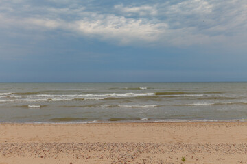 Baltic sea shore (sand dunes) at cloudy day. Soft light, waves and water splashes. Idyllic seascape. Ventspils, Latvia, Europe.