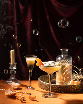 Refreshing orange cocktail with tangerines,liquer,tonic,with candle,bubbles,burgundy,velvet curtain in new vawe style.Conceptual photo of drinks.