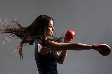 beautiful girl exercising karate punch against gray background