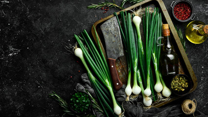 Green onion heads on the kitchen table. Top view. On a black background. Rustic style.