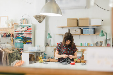 Focused woman sewing clothes in workshop