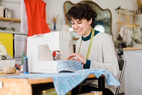 Focused tailor sewing on machine in atelier