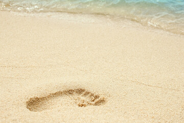 A Beach travel - woman relaxing walking on a sandy beach leaving footprints in the sand. Close up detail of female feet on golden sand at a beach in Greece. Background.