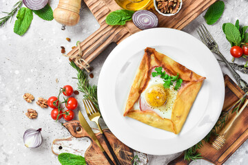 breakfast Scrambled eggs with pancakes and vegetables. On a white plate. On a gray stone background. Restaurant menu.