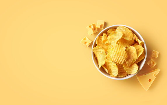 Bowl Of Crispy Potato Chips Or Crisps With Cheese Flavor On Light Yellow Background