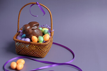 Chocolate bunny and candy eggs in an antique basket, with space for text.