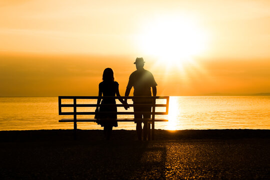 A happy couple on a bench by the sea on nature in travel silhouette