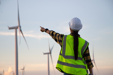 asian female engineer using drone for  inspection wind turbine farm in evening.