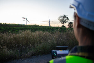 asian female engineer using drone for  inspection wind turbine farm in evening.