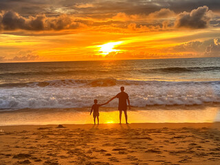 Fototapeta premium Father and son sitting on the beach in the evening