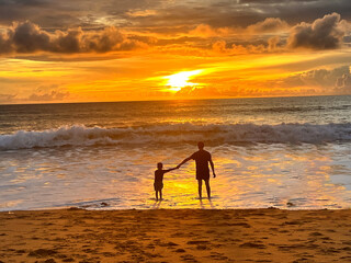 Father and son sitting on the beach in the evening