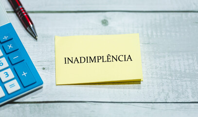 A palavra inadimplência em Português do Brasil escrita em um pedaço de papel que está sobre uma...