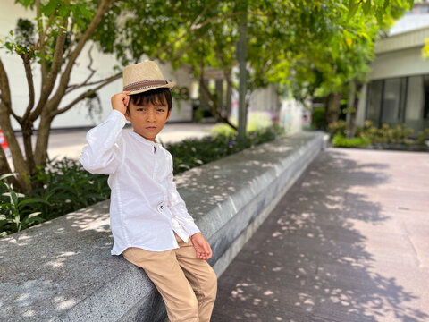 A young boy wearing a white shirt and a hat