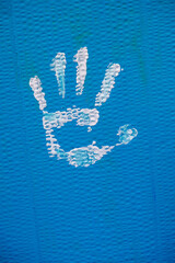 trace de main avec de la peinture sur une surface en carton bleu