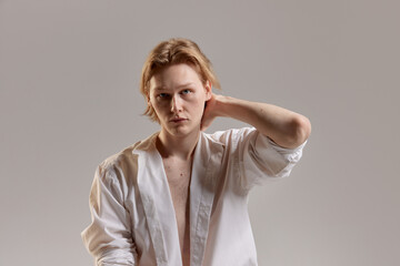 Portrait of young redhead man posing in white shirt over grey studio background. Casual man's fashion, comfort and wellness. Concept of men's health, body and skin care, hygiene and male cosmetology