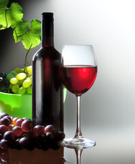 Bottle with wine glass with red wine and branch grape on light background
