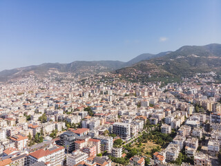 Top view of the tourist city of Alanya in Turkey, low-rise buildings of the city from above against the backdrop of mountains, on a sunny summer day