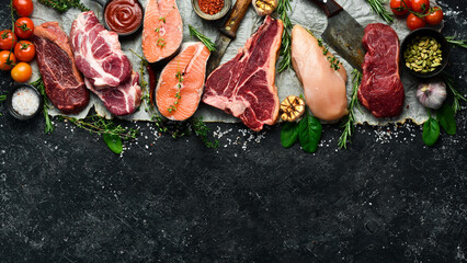 Set of meat. Fish steak, veal steak and chicken breast. Top view. On a black stone background. © Yaruniv-Studio