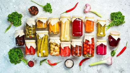 Jars with various pickled vegetables on a stone background. On a stone background. Top view.