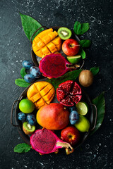 Background of exotic fruits. Ripe tropical fruits on a stone background. Copy space. Top view.