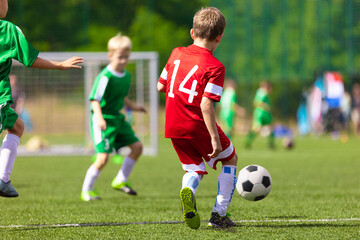 School children in soccer game. Football match for school kids. Young soccer player kicking ball...