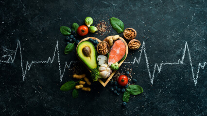 Fototapeta Food banner. Healthy foods low in carbohydrates. Food for heart health: salmon, avocados, blueberries, broccoli, nuts and mushrooms. On a black stone background. Top view. obraz