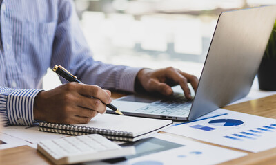 Fototapeta premium Businessman working with laptop and analyzing financial document data for budget accounting.