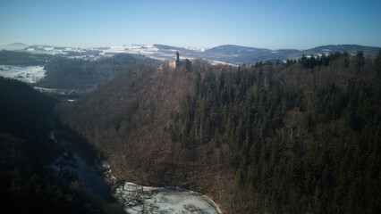 Aerial top view of Grodno castle in Zagorze in Owl Mountains with beautiful winter landscape. Old historical fortress in mountains, covered with forest. 