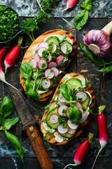 Vegan Sandwich with radish, cucumber, cheese and basil. Bruschetta. Top view. On a stone background.