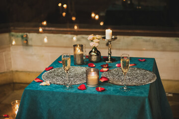 Romantic Date Wedding Concept. Served Table with Champagne And Burning Candles In Restaurant Interior At Night. No People