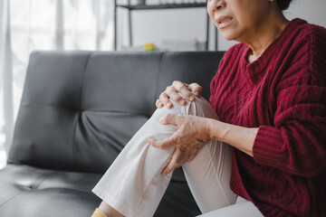 Elderly asian housewife woman sitting on sofa. knee pain