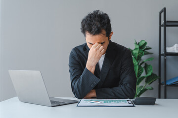 Young handsome asia business man in formal suit working with monthly report balance sheet and yearly tax of accounting to verify the account by an authorized auditor