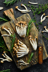 Brown beech mushrooms or Shimeji mushroom on a wooden kitchen board. on a black stone table. Top view.