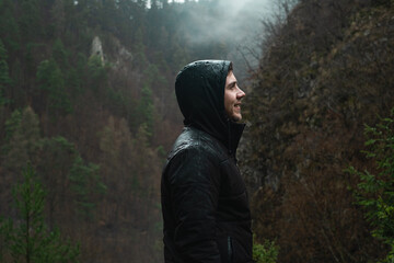 Carefree happy man enjoying nature in a grassy meadow on top of a mountain cliff. Brasov, Romania, Europe