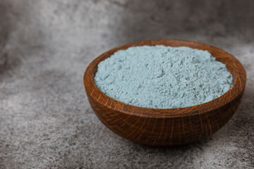 Blue spirulina powder in a bowl on a black marble background. Natural superfood, vegan, healthy food supplement. Phycocyanin extract. Antioxidant. Place for text. Copy space.