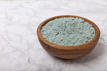 Blue spirulina powder in a bowl on a white marble background. Natural superfood, vegan, healthy food supplement. Phycocyanin extract. Antioxidant. Place for text. Copy space.