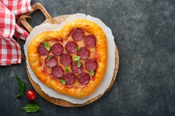 Valentines day heart shaped pizza with mozzarella, pepperoni and basil, wine bottle, two wineglass, gift box on black background. Idea for romantic dinner Valentines day. Top view. Mock up.