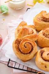 Easter breakfast Holliday concept. Easter bunny buns rolls with cinnamon made from yeast dough with orange glaze, easter decorations, colored eggs on pink spring background. Easter Holliday card.