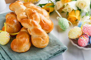 Easter breakfast Holliday concept. Easter bunny buns rolls with cinnamon made from yeast dough with orange glaze, easter decorations, colored eggs on white spring background. Easter Holliday card.