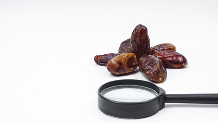 Kurma or dates fruits isolated with magnifiying glass on white background