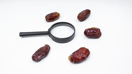 Kurma or dates fruits isolated with magnifiying glass on white background