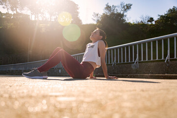 Sporty woman runner sitting on the road recovering after jogging