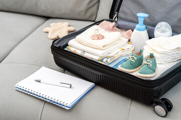 Open bag for maternity hospital. Suitcase of baby clothes prepared for newborn birth. Concept of...