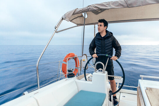 Confident man standing at steering wheel of yacht