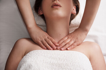 masseur massaging decollete and neck of young woman on massage table. Concept of massage spa...
